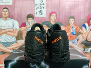 Rear view of the black Nike sneakers showing orange embroidered heel branding and textured panels.