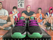 Front view of black basketball sneakers with purple laces, green toe outsoles, and contrasting graphic details.