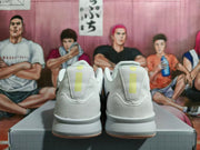 Rear view of light gray-white Nike basketball shoes with pale lime heel accents.