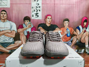 Front view of gray-purple Nike Mind sneakers with orange outsole accents displayed on a Nike shoe box.