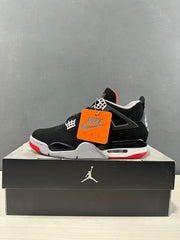 Side profile of a black Jordan Air Jordan 4 sneaker with white lace supports, red outsole accents, and an orange hangtag.