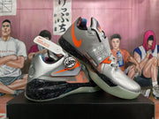 Pair of silver and orange basketball shoes displayed at an angle, showing the straps and speckled midsoles.