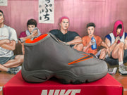 Side profile of a gray high-top sneaker with an orange-accented side mark, sculpted gray midsole, and black outsole sections.