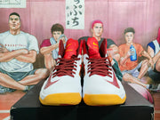 Front view of red and white high-top basketball shoes with dark red laces, red tongue panels, visible swooshes, and yellow toe outsoles.