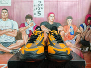 Front view of a pair of orange and black basketball sneakers showing the toe design, laces, and visible branding.