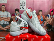 Angled view of paired white Nike sneakers showing the red Swoosh, anime graphics, gray detailing, and ridged outsoles.