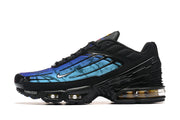 Side profile of a black Nike Air Max Plus TN sneaker with a blue gradient panel and visible sole cushioning.