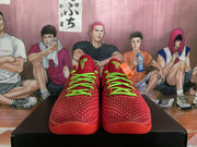 Front view of red textured basketball sneakers with bright green laces and green tongue logos.