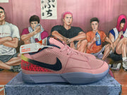 Side view of a pink Nike sneaker showing the black Swoosh, mesh upper, perforated forefoot, red patterned heel panel, and contrasting sole.