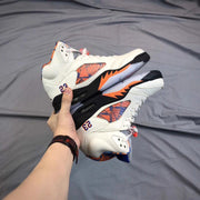 Two white high-top sneakers held together, showing the patterned side panels and contrasting orange, blue, black, and translucent sole details.