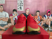 Front view of red Nike basketball sneakers with gold toe panels, perforated forefoot sections, red laces, and black outsoles.