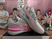 Pair of white, pink, and gray Nike sneakers shown from the side on a box.