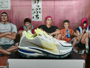 Side profile of a white Nike basketball shoe with yellow panels, a gold-tone swoosh, and blue outsole.