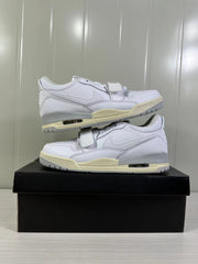 Pair of white low-top sneakers stacked on a black box, showing side profiles and cream midsole accents.