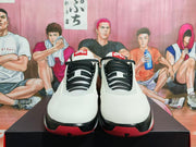 Front view of white Jordan high-top shoes with black rope-style laces and red outsole accents.