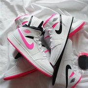 White mid-top sneakers arranged to show pink and black Swooshes and outsoles