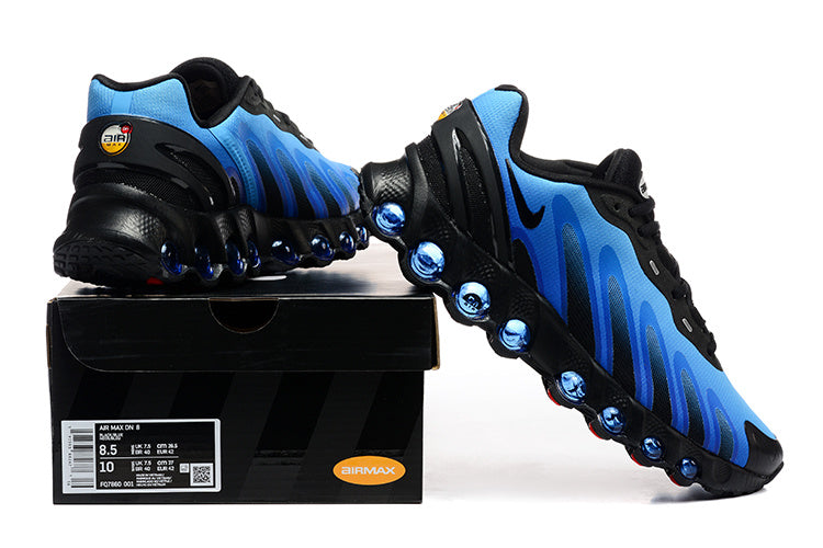 Blue and black Nike Air Max DN8 sneakers shown with a shoe box; the box label shows a sample size.