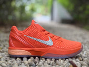 Close side view of the orange sneaker showing its textured upper, silver Swoosh, and layered sole.