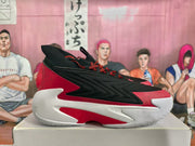 Side view of black and red basketball sneakers resting on a shoebox.