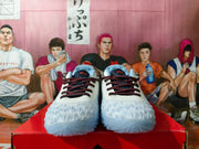 Front view of white sneakers with dark patterned laces, pale blue lining, and red details.