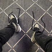 Top-down view of the sneakers being worn, showing the perforated grey toe boxes and black laces.