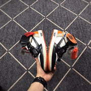 Top-down view of the pair showing black overlays, white panels, orange accents, and contrasting sole edges.