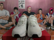 Front view of white Nike sneakers with black Swoosh details, white laces, and black toe and outsole accents.