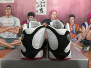Rear view of black and white high-top sneakers showing white heel panels, black overlays and red outsole accents.