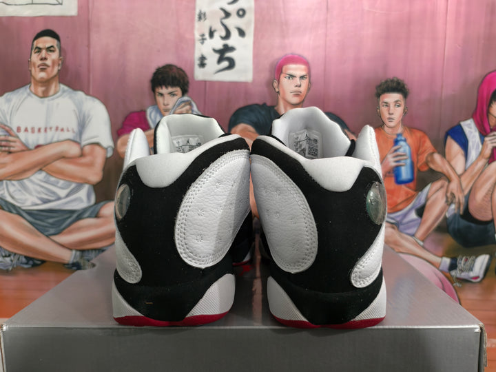 Rear view of black and white high-top sneakers showing white heel panels, black overlays and red outsole accents.
