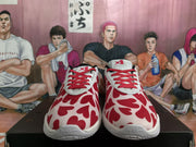 Front view of white and red Nike sneakers with red laces and a repeating red heart-like upper pattern.