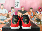 Rear view of red basketball shoes showing black heel panels, gold bars, and white soles.