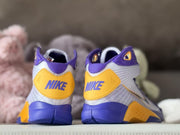 Rear view showing gold heel panels with Nike branding and purple midsoles.