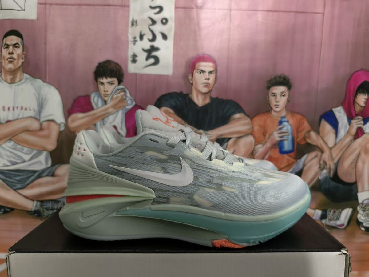 Gray Nike basketball sneaker shown in profile on a box, with a side Swoosh and red outsole detail.