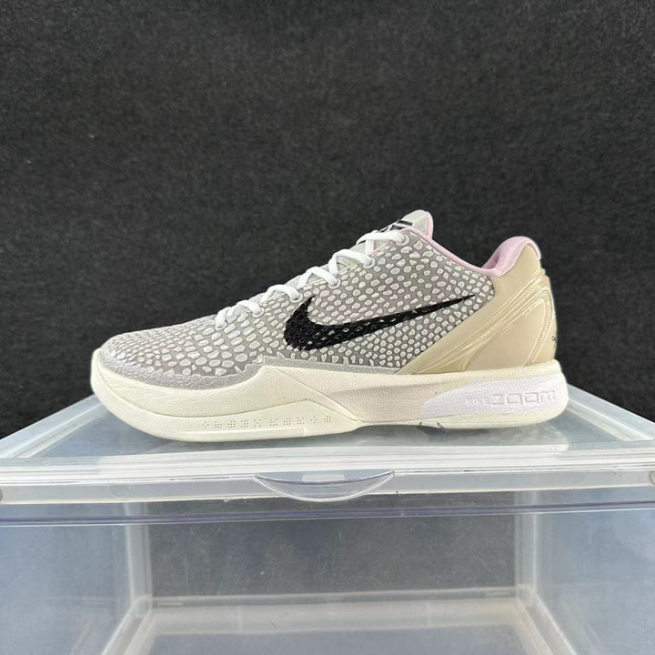 Side view of a gray patterned Nike basketball shoe with a black Swoosh, pale yellow heel panel, pink collar lining, and light sole.