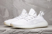 Pair of white low-top sneakers shown from a front three-quarter angle with matching laces and textured uppers.