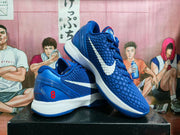 Angled view of the blue and white sneakers showing the side Swooshes, red heel number 8 and layered sole structure.