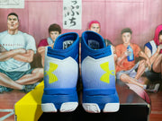 Rear view showing the blue padded collars, white heel panels, and yellow Under Armour logos.