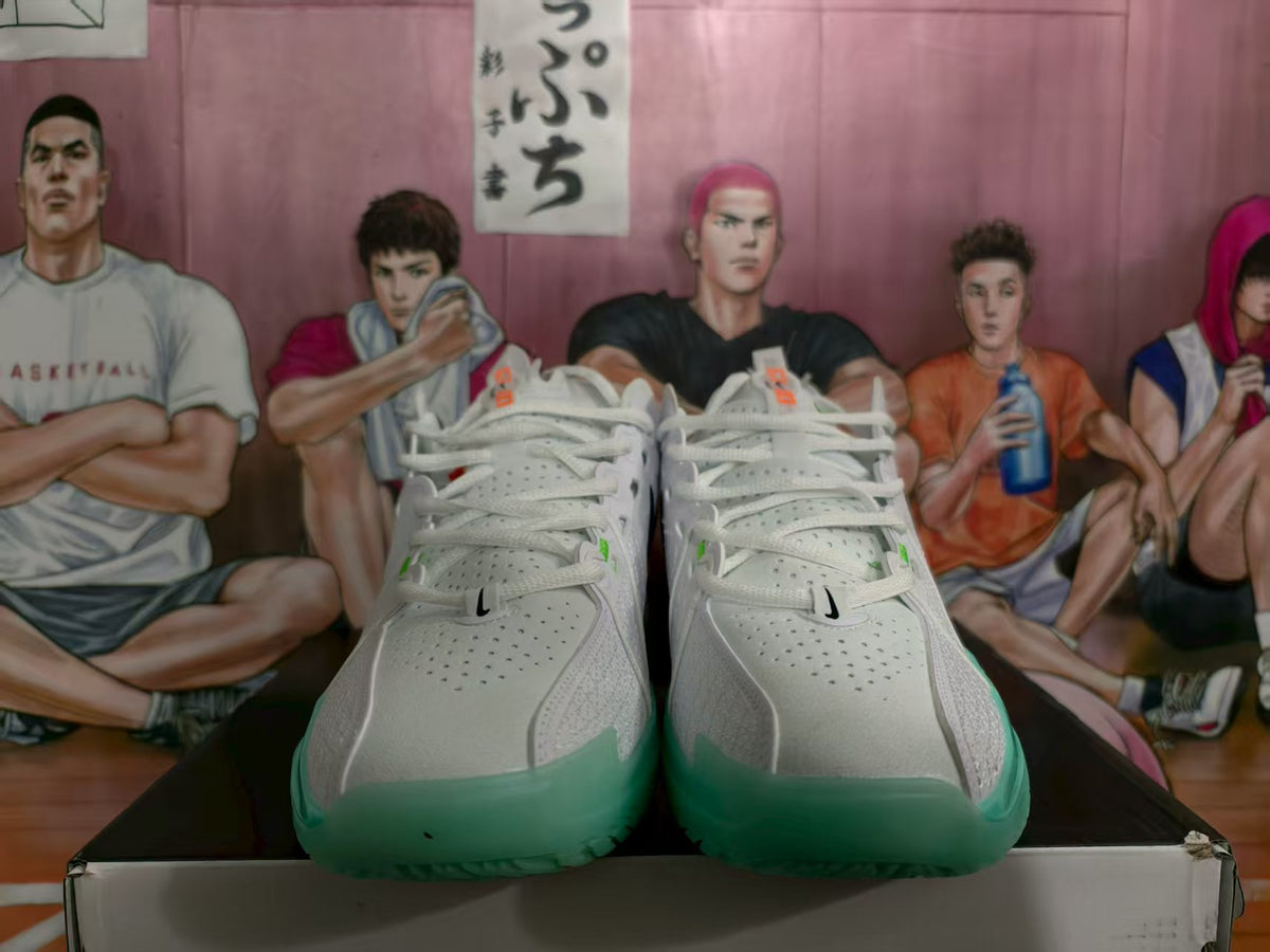 Front view of white Nike basketball sneakers with green toe-area accents and perforated uppers.