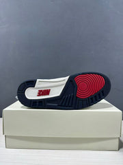Outsole view of the white, blue, and dark navy Jordan sneakers resting on a shoebox.