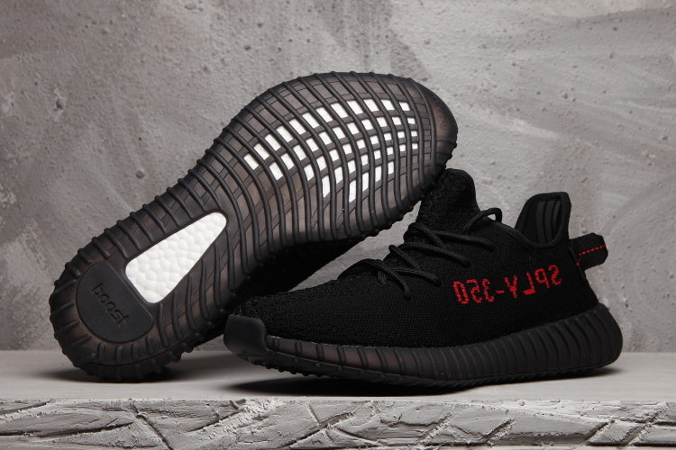 Black Yeezy 350 V2-style sneakers shown from the side and sole, with red side lettering and a ribbed black outsole.