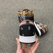 Rear view showing black paisley heel panels, brown patterned collars, pink accent trim, and white midsoles.