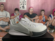 Side profile of the white and gray basketball sneakers showing the Swoosh, lace-up upper, textured toe area, and black outsole.