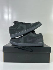 Two dark grey and black low-top sneakers displayed stacked on a shoebox
