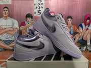 Angled view of the purple and gray sneaker pair, showing the side details, padded collars, heel pulls, and flat soles.