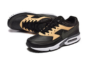 Angled view of black and tan Nike Air Max lace-up sneakers.