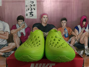 Front view of the pair showing the perforated forefoot, molded construction, and green textured soles.