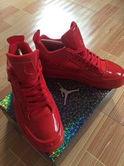 Pair of glossy red high-top sneakers displayed on a patterned Jordan box.