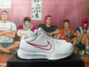 Side view of a white basketball shoe with a red Swoosh and perforated toe area.