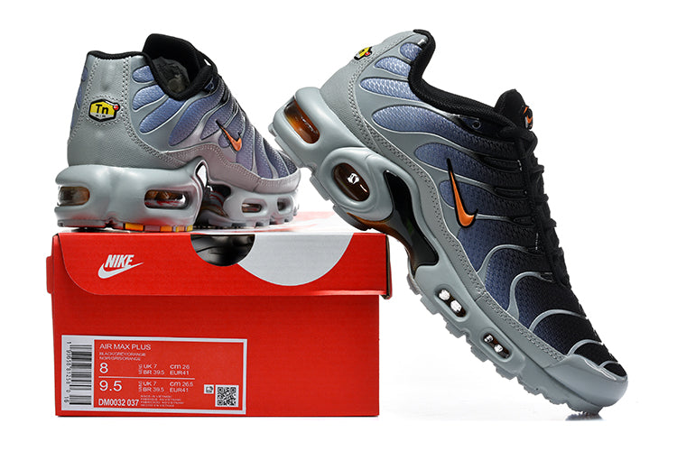 Nike Air Max Plus sneakers in black, grey and orange beside a box showing a sample size label