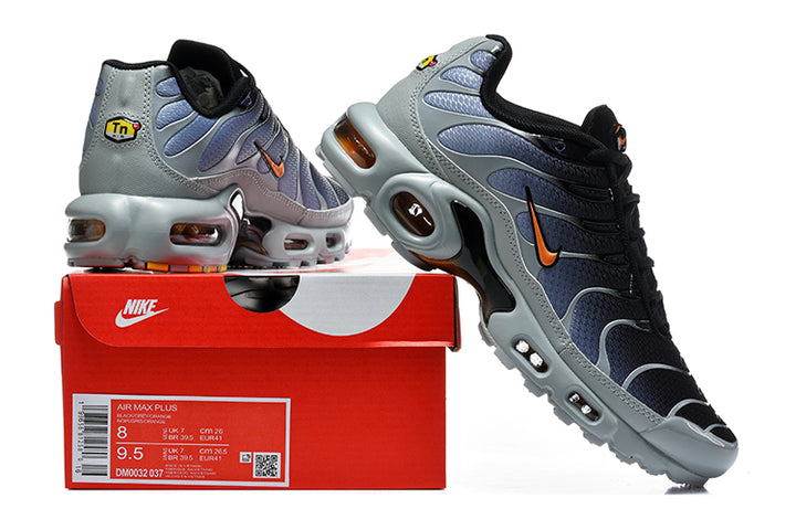 Nike Air Max Plus sneakers in black, grey and orange beside a box showing a sample size label